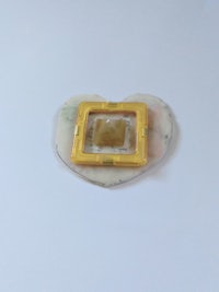 a yellow heart shaped brooch on a white surface